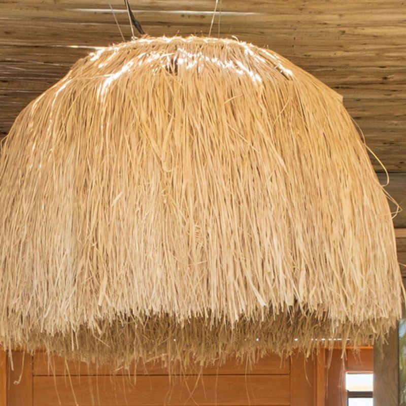A large raffia pendant lamp with a fringed edge.